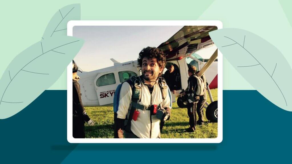 A man smiling with his thumbs up standing outside a plane.